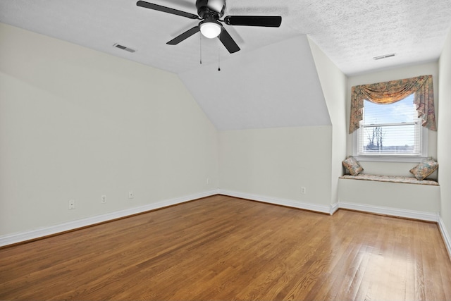 additional living space with hardwood / wood-style flooring, ceiling fan, lofted ceiling, and a textured ceiling