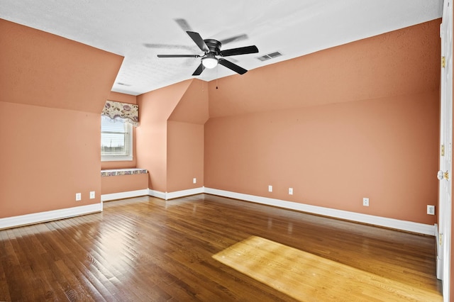 additional living space with vaulted ceiling, hardwood / wood-style floors, a textured ceiling, and ceiling fan