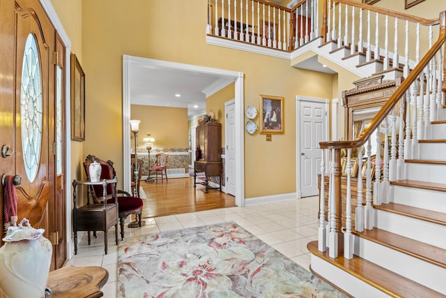 entrance foyer with crown molding, light tile patterned floors, and a towering ceiling