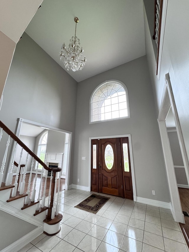 foyer entrance with baseboards, a chandelier, a towering ceiling, and light tile patterned floors