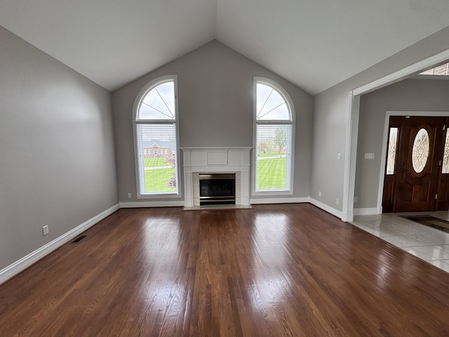 unfurnished living room featuring vaulted ceiling, wood finished floors, visible vents, and a wealth of natural light