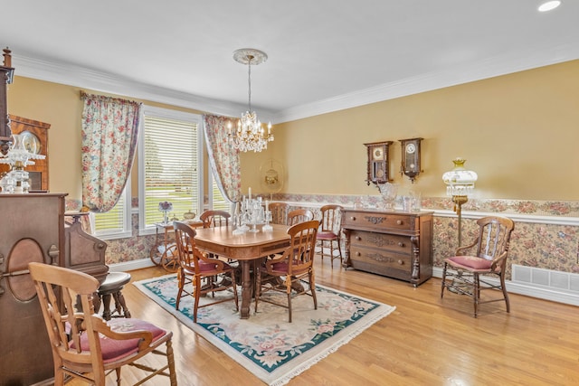 dining space with crown molding, an inviting chandelier, and light wood-type flooring