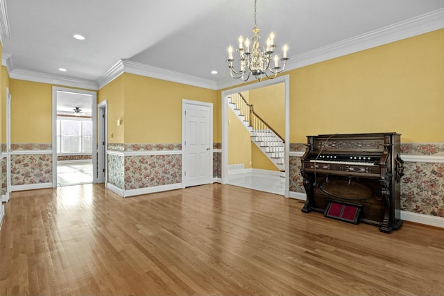 dining room featuring a wainscoted wall, wood finished floors, a notable chandelier, and stairway