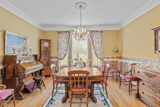 dining space featuring an inviting chandelier, ornamental molding, and light hardwood / wood-style floors