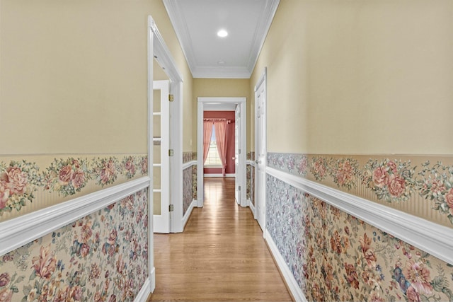 hallway featuring wallpapered walls, light wood-style flooring, and crown molding