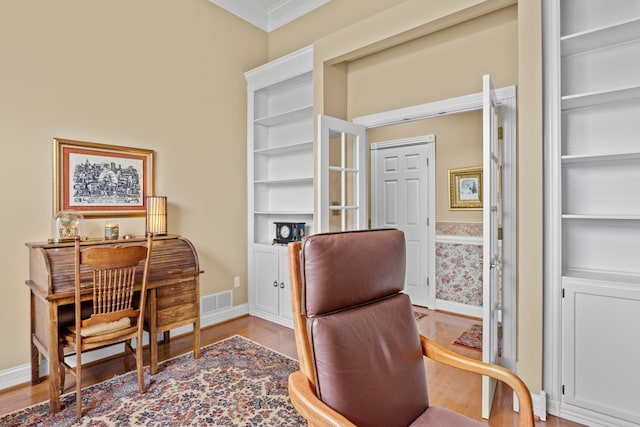 office area featuring crown molding, built in shelves, and light hardwood / wood-style flooring