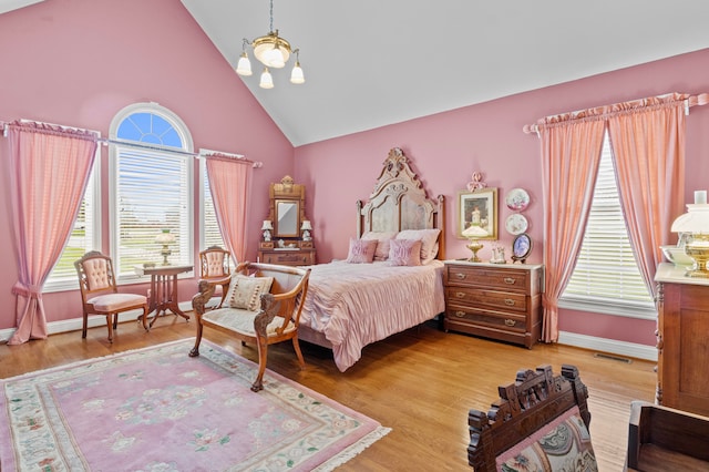 bedroom with an inviting chandelier, high vaulted ceiling, and light wood-type flooring