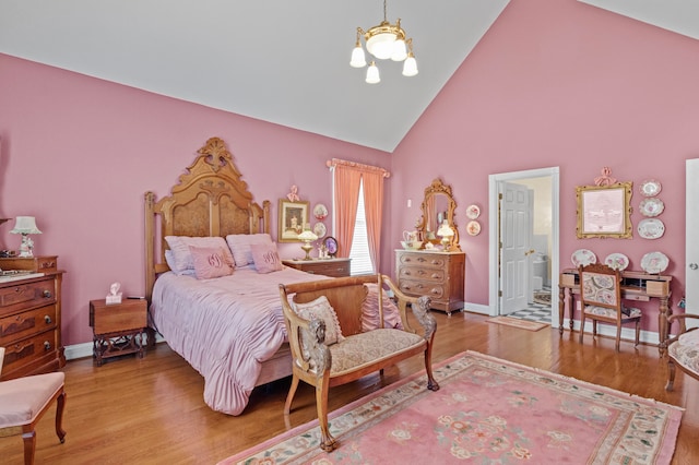 bedroom featuring high vaulted ceiling, ensuite bathroom, and hardwood / wood-style floors