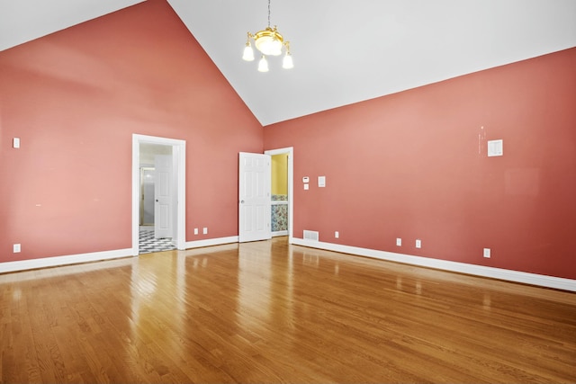 empty room featuring baseboards, visible vents, a chandelier, wood finished floors, and high vaulted ceiling