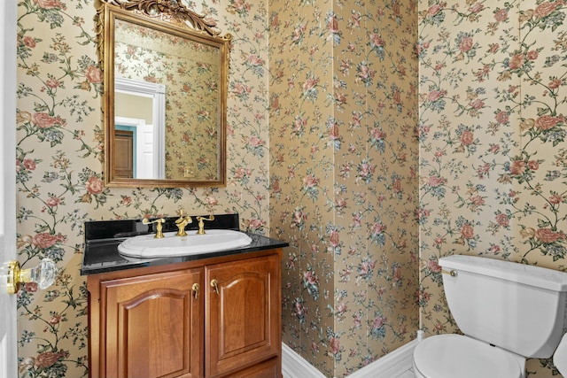 half bath featuring wallpapered walls, vanity, and toilet