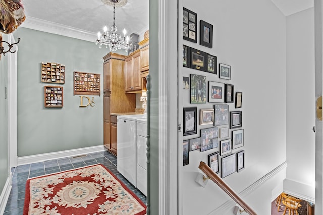 laundry room featuring a chandelier, ornamental molding, baseboards, washer and dryer, and cabinet space