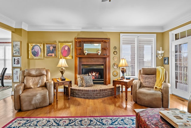 living room with ornamental molding, wood-type flooring, and a brick fireplace