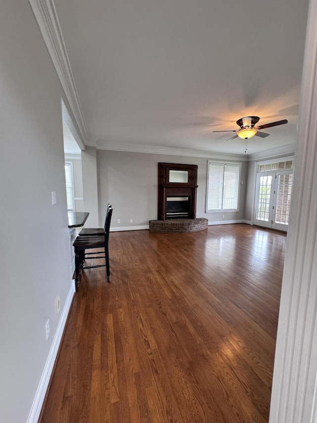 unfurnished living room featuring baseboards, ornamental molding, a brick fireplace, and dark wood-style floors