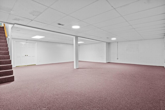 finished below grade area featuring concrete block wall, stairway, a drop ceiling, and carpet