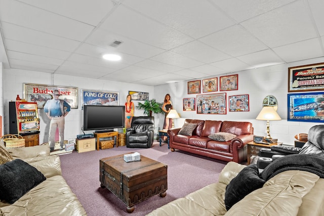 living room with a drop ceiling and carpet