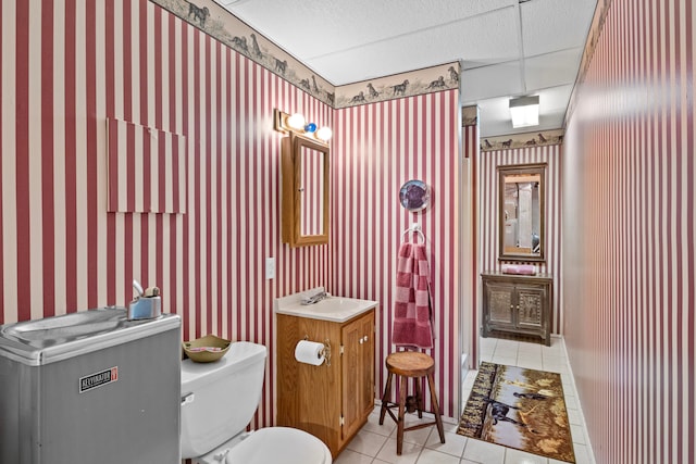 bathroom with vanity, tile patterned floors, toilet, and a drop ceiling