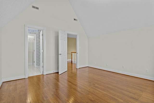 unfurnished bedroom with vaulted ceiling, visible vents, and wood finished floors