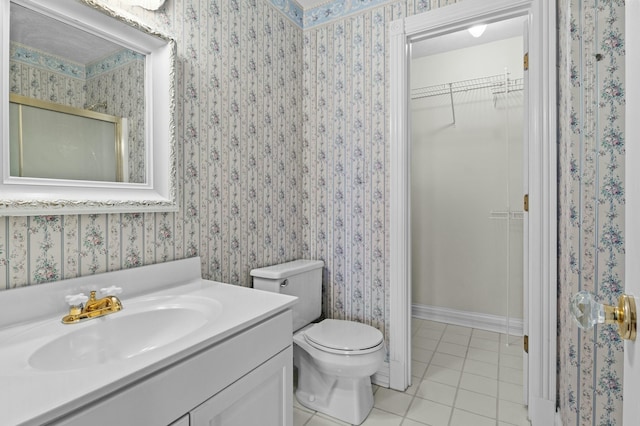 bathroom with tile patterned floors, wallpapered walls, a spacious closet, vanity, and toilet