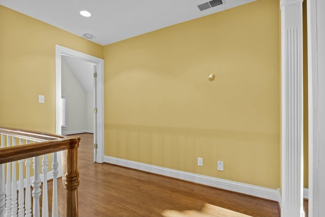 spare room with baseboards, wood finished floors, visible vents, and vaulted ceiling