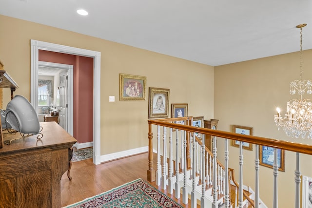 corridor with light hardwood / wood-style floors and a notable chandelier