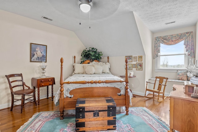 bedroom featuring dark wood-type flooring, vaulted ceiling, and a textured ceiling