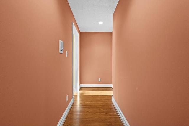 hall with recessed lighting, a textured ceiling, baseboards, and dark wood-style flooring