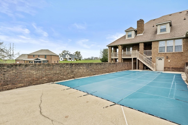 view of pool with fence, a fenced in pool, stairway, and a patio