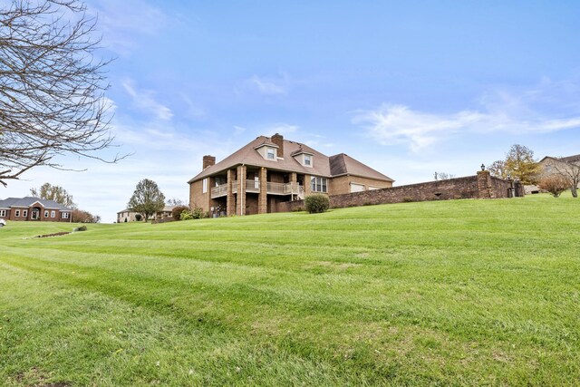 back of house featuring a lawn, brick siding, and a chimney