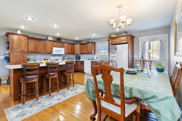 dining area featuring a chandelier, sink, and light hardwood / wood-style flooring