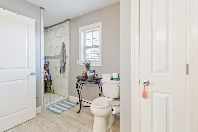 bathroom featuring toilet, tile patterned flooring, and a tile shower