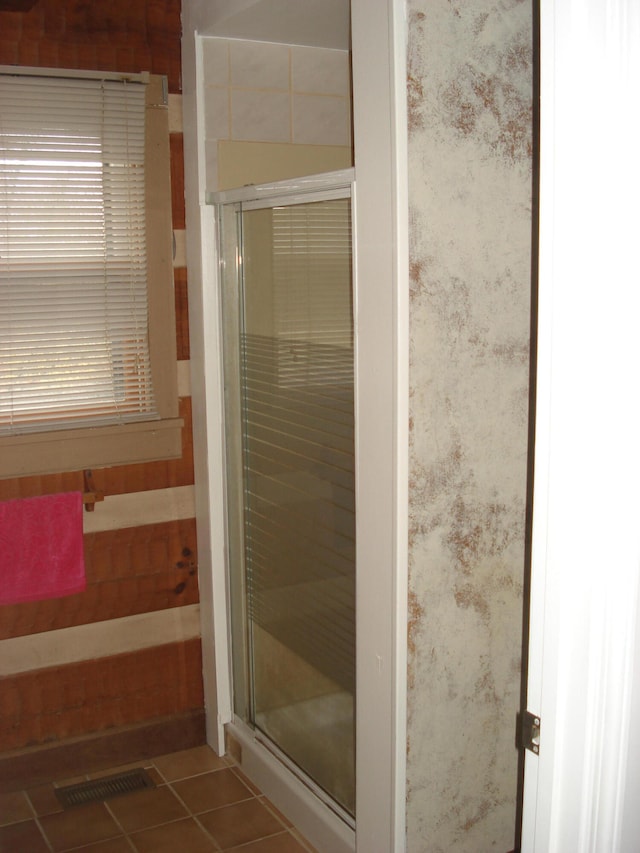 bathroom with tile patterned floors and a shower with door