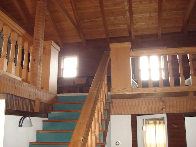 stairs with wood ceiling, vaulted ceiling with beams, and a healthy amount of sunlight