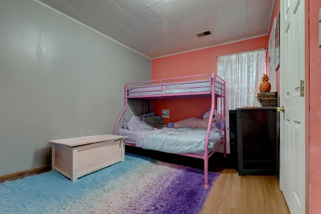 bedroom with ornamental molding and hardwood / wood-style floors