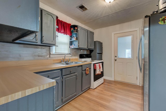 kitchen with sink, stainless steel refrigerator, light hardwood / wood-style floors, and white range with electric cooktop