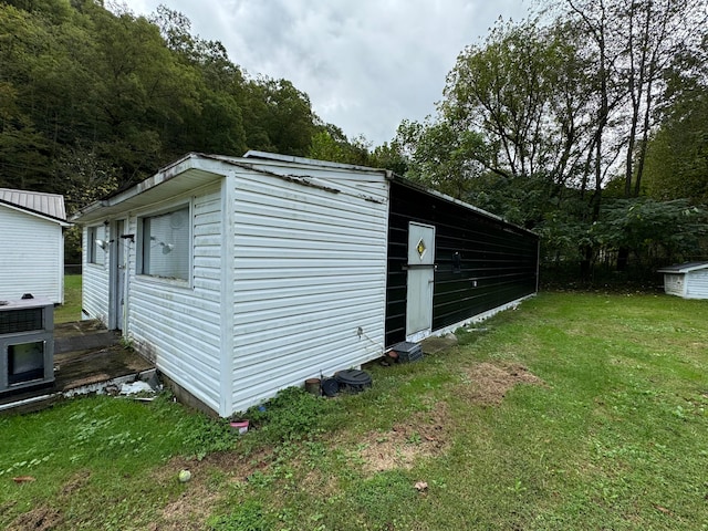 view of side of property featuring a lawn and an outdoor structure