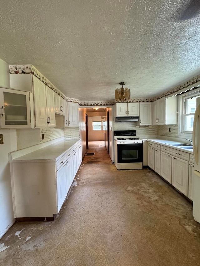 kitchen featuring white gas range oven, decorative backsplash, a textured ceiling, sink, and white cabinetry