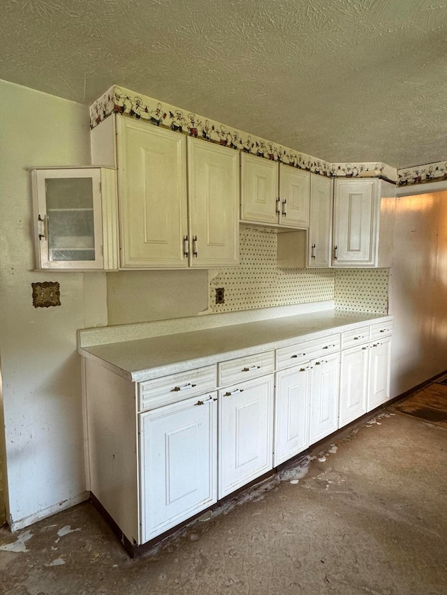 kitchen with white cabinets, a textured ceiling, and backsplash