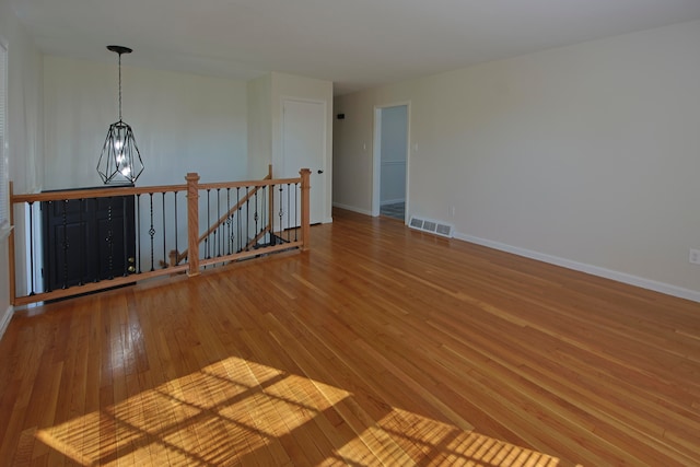 empty room featuring hardwood / wood-style flooring and a chandelier