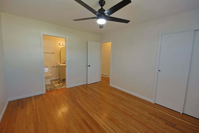 unfurnished bedroom featuring light hardwood / wood-style floors, ceiling fan, a closet, and ensuite bathroom