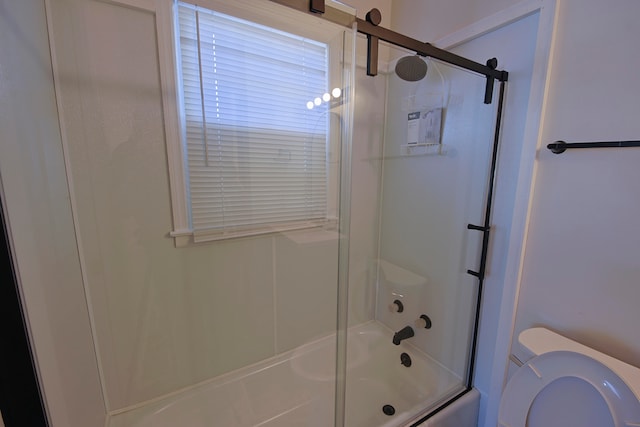 bathroom with combined bath / shower with glass door and toilet