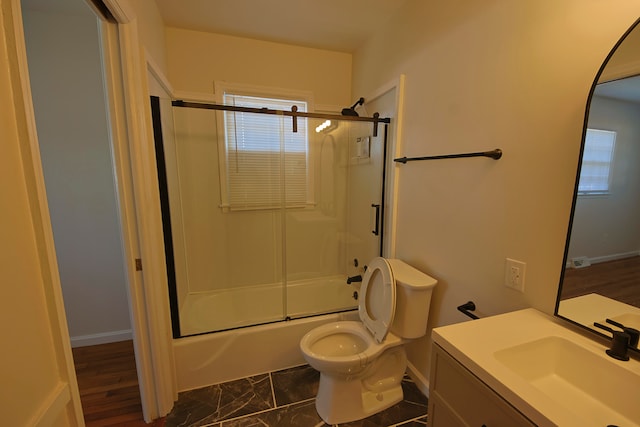 full bathroom with hardwood / wood-style flooring, bath / shower combo with glass door, vanity, and toilet