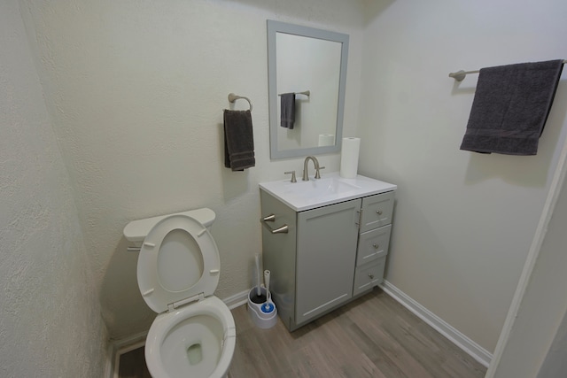 bathroom with toilet, vanity, and hardwood / wood-style flooring