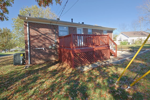 rear view of property with a wooden deck, a lawn, and central AC