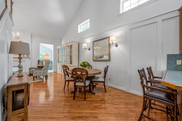 dining area featuring high vaulted ceiling and light hardwood / wood-style floors