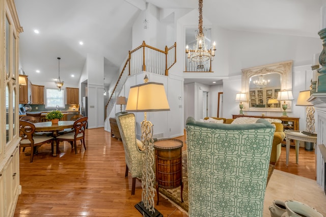 dining space featuring high vaulted ceiling, a notable chandelier, light hardwood / wood-style floors, and a fireplace