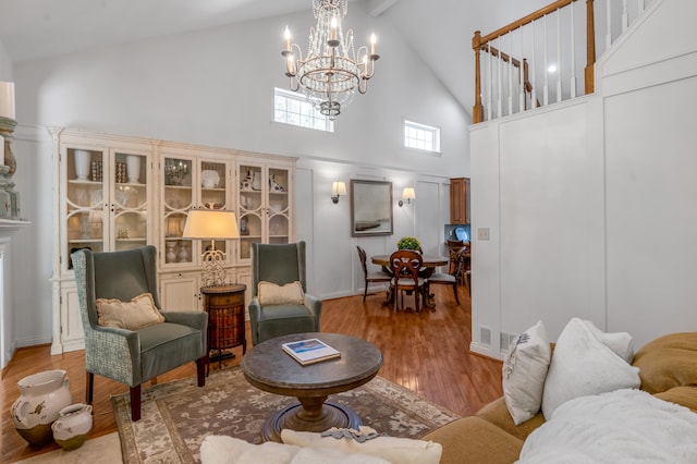 living room featuring an inviting chandelier, beamed ceiling, light hardwood / wood-style flooring, and high vaulted ceiling