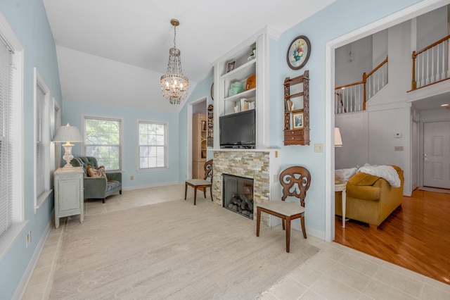 sitting room featuring a stone fireplace, a chandelier, vaulted ceiling, and light hardwood / wood-style flooring