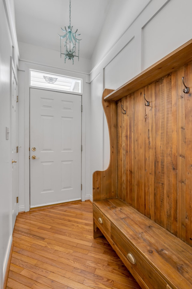 mudroom with light hardwood / wood-style floors, an inviting chandelier, and vaulted ceiling