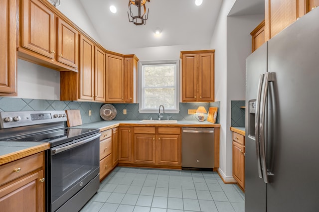 kitchen with stainless steel appliances, sink, vaulted ceiling, tile counters, and decorative backsplash