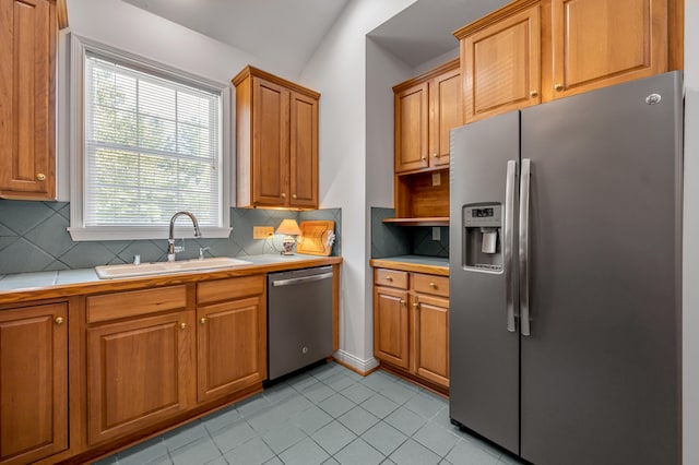 kitchen with sink, appliances with stainless steel finishes, tasteful backsplash, light tile patterned floors, and vaulted ceiling